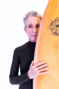 Woman with grey hair holding surfboard